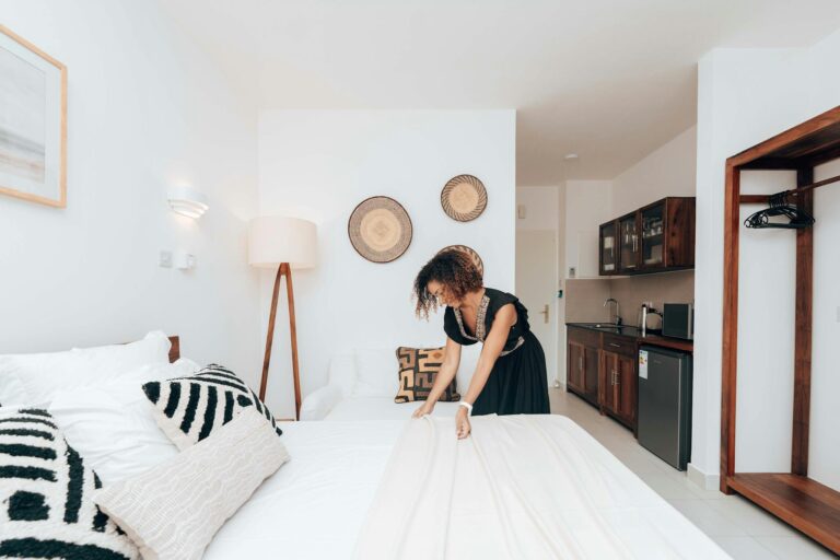 Elegant hotel suite in Zanzibar with modern interior and a woman arranging the bed.