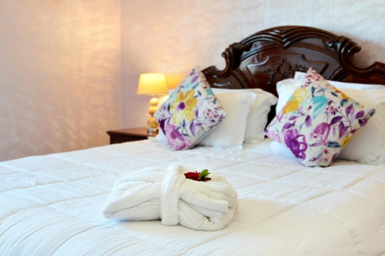 Inviting hotel room featuring a neatly made bed with floral pillows and a decorative towel.